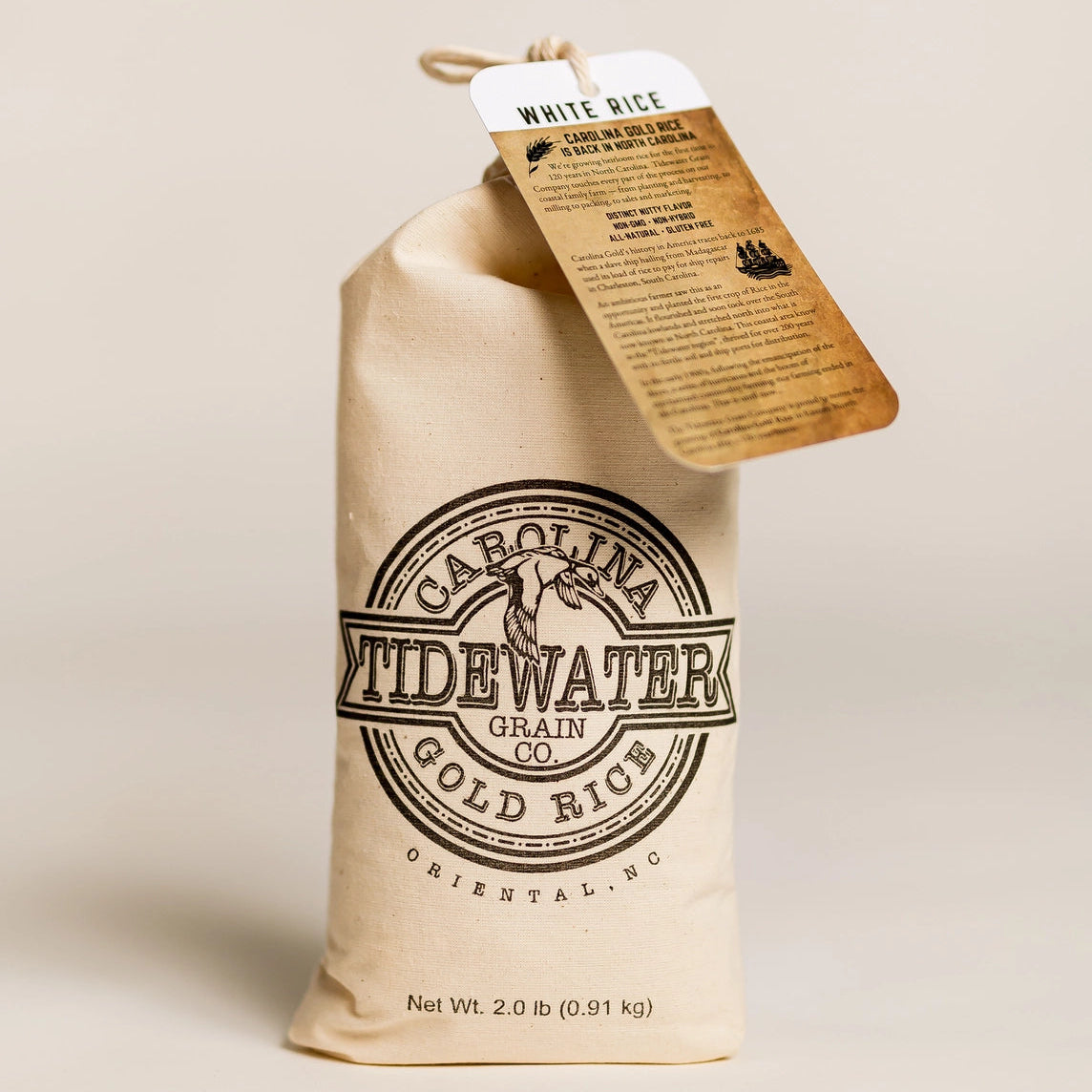 Bag of Carolina Tide Water Gold Rice with a tag on a beige background
