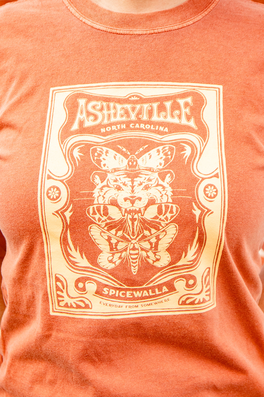 Orange t-shirt with a graphic design featuring text and butterfly illustration.