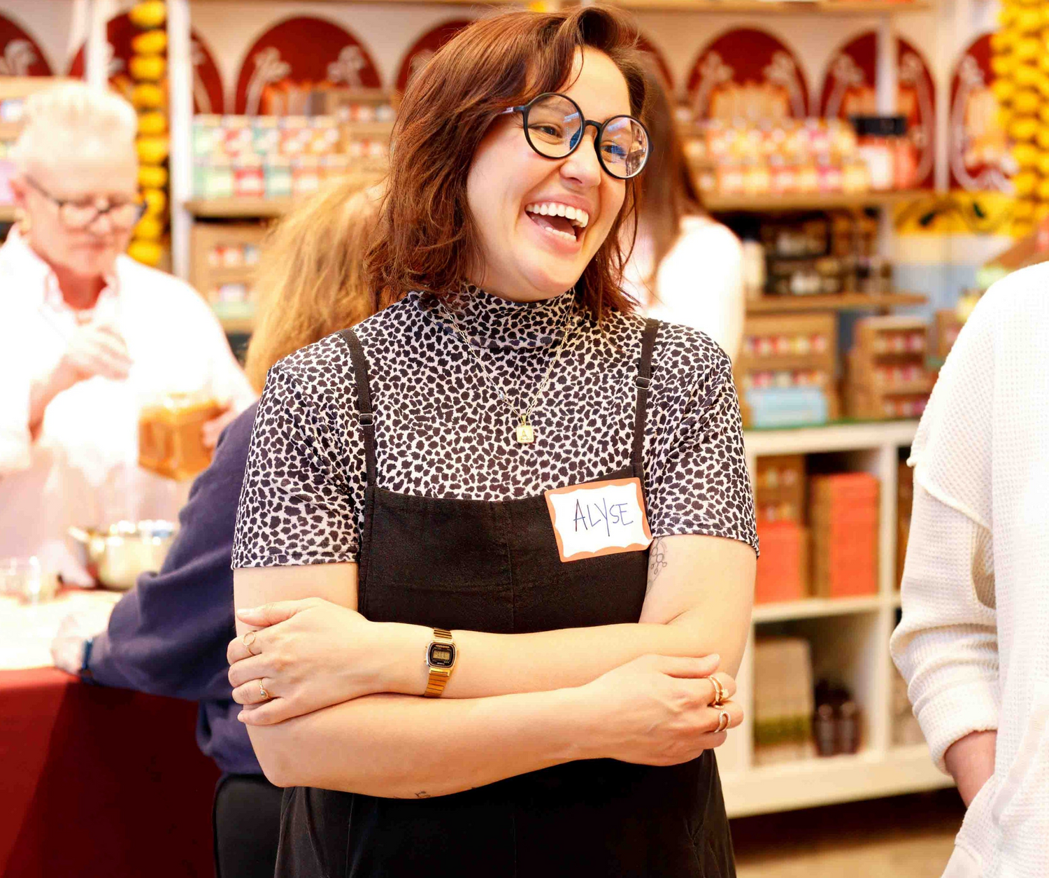 Person wearing a black apron with a name tag in a store setting