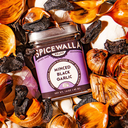 Spicewalla minced black garlic jar surrounded by garlic bulbs
