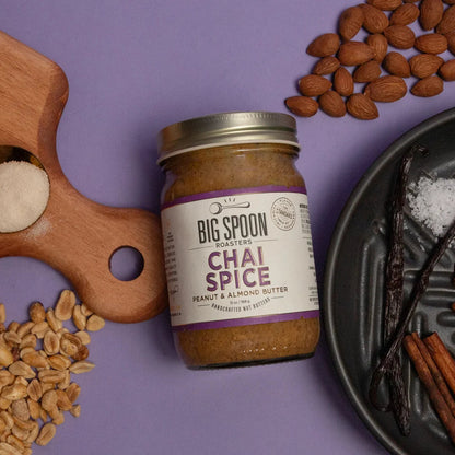 Jar of 'Big Spoon' Chai Spice peanut and almond butter on a purple background with ingredients around it.