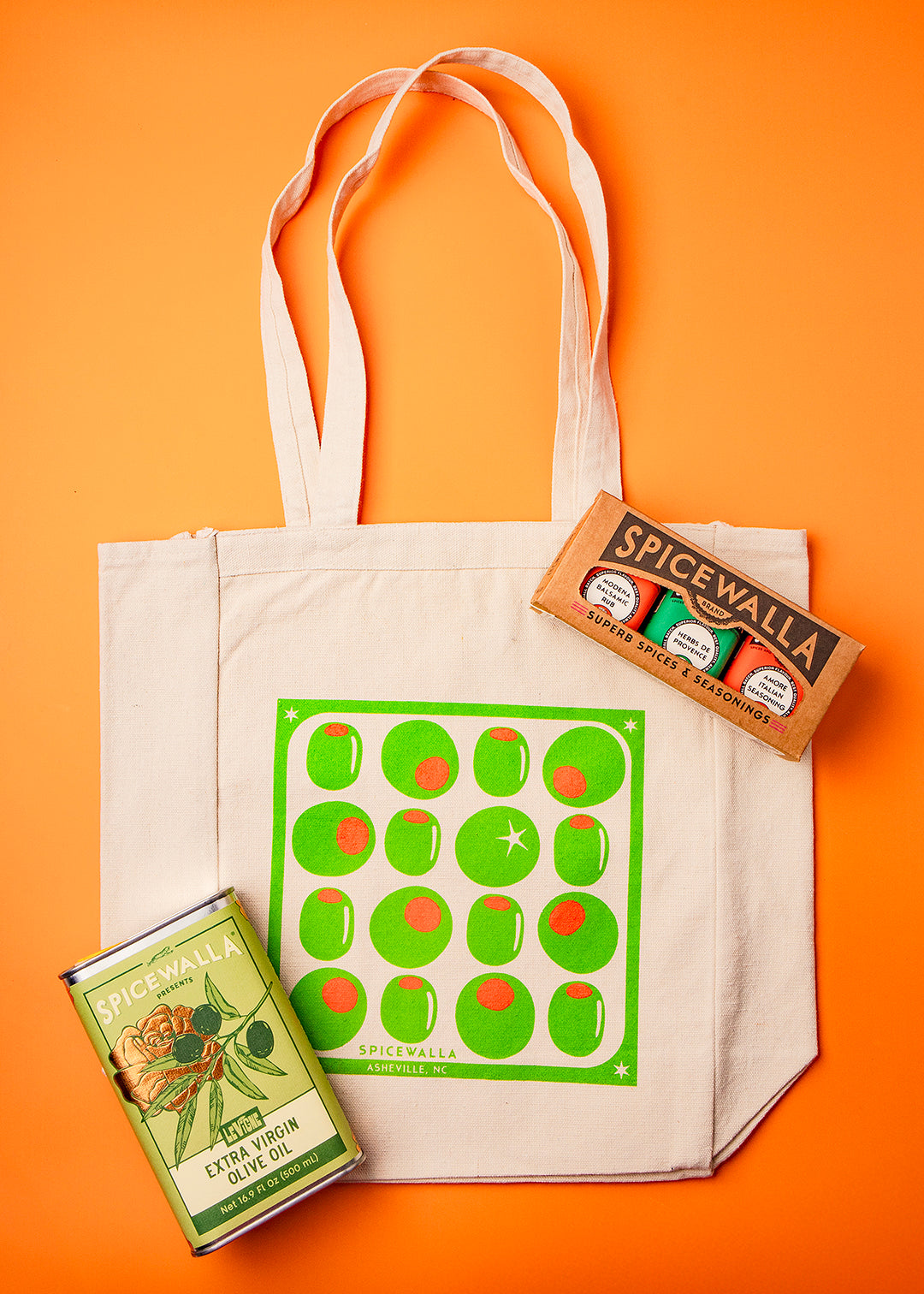 Tote bag with green pattern, Spicewalla spice box, and green label on an orange background
