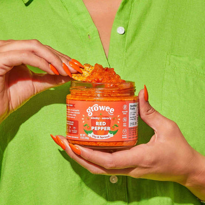 Person wearing a green shirt holding a jar of hot sauce with visible branding.