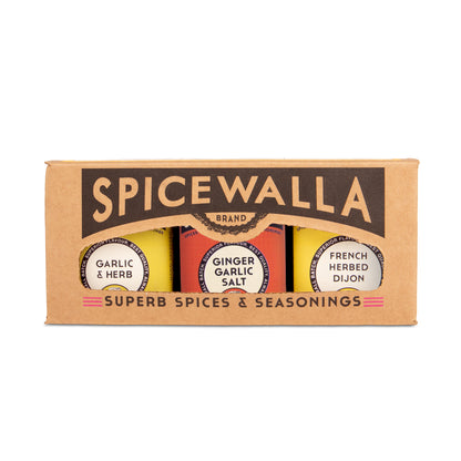 Spicewalla brand gift set containing three jars of spices and seasonings in a brown cardboard box. The jars are labeled Garlic & Herb, Ginger Garlic Salt, and French Herbed Dijon.