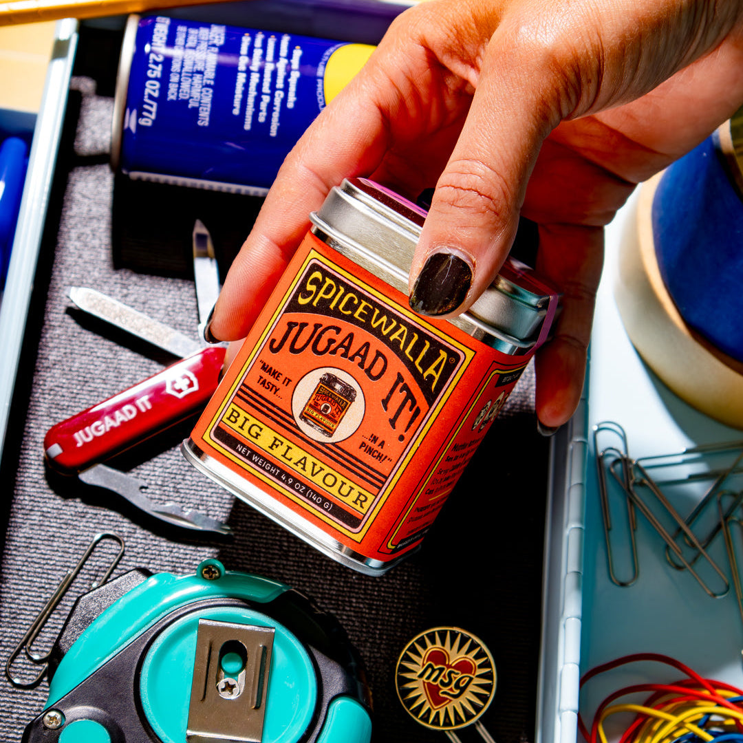 Person holding a Spicewalla jugaad it! container in an open drawer with stationery items.