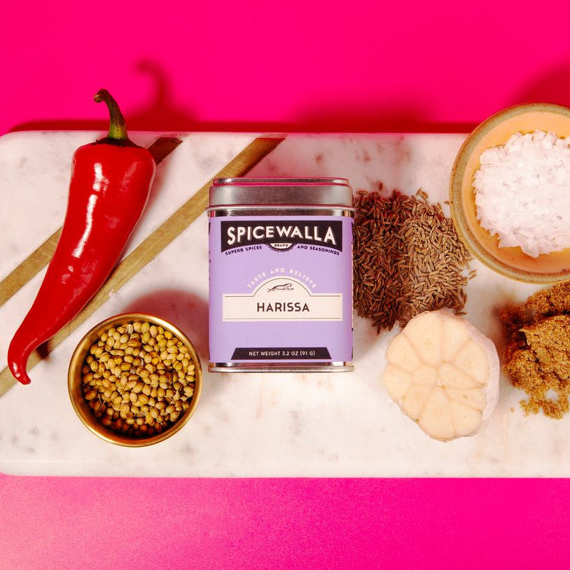Spicewalla Harissa spice can with ingredients on a pink background