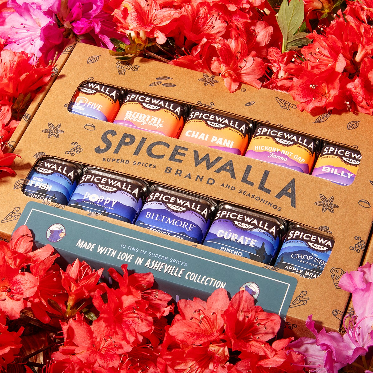 Spicewalla seasoning packets in a cardboard box surrounded by pink flowers
