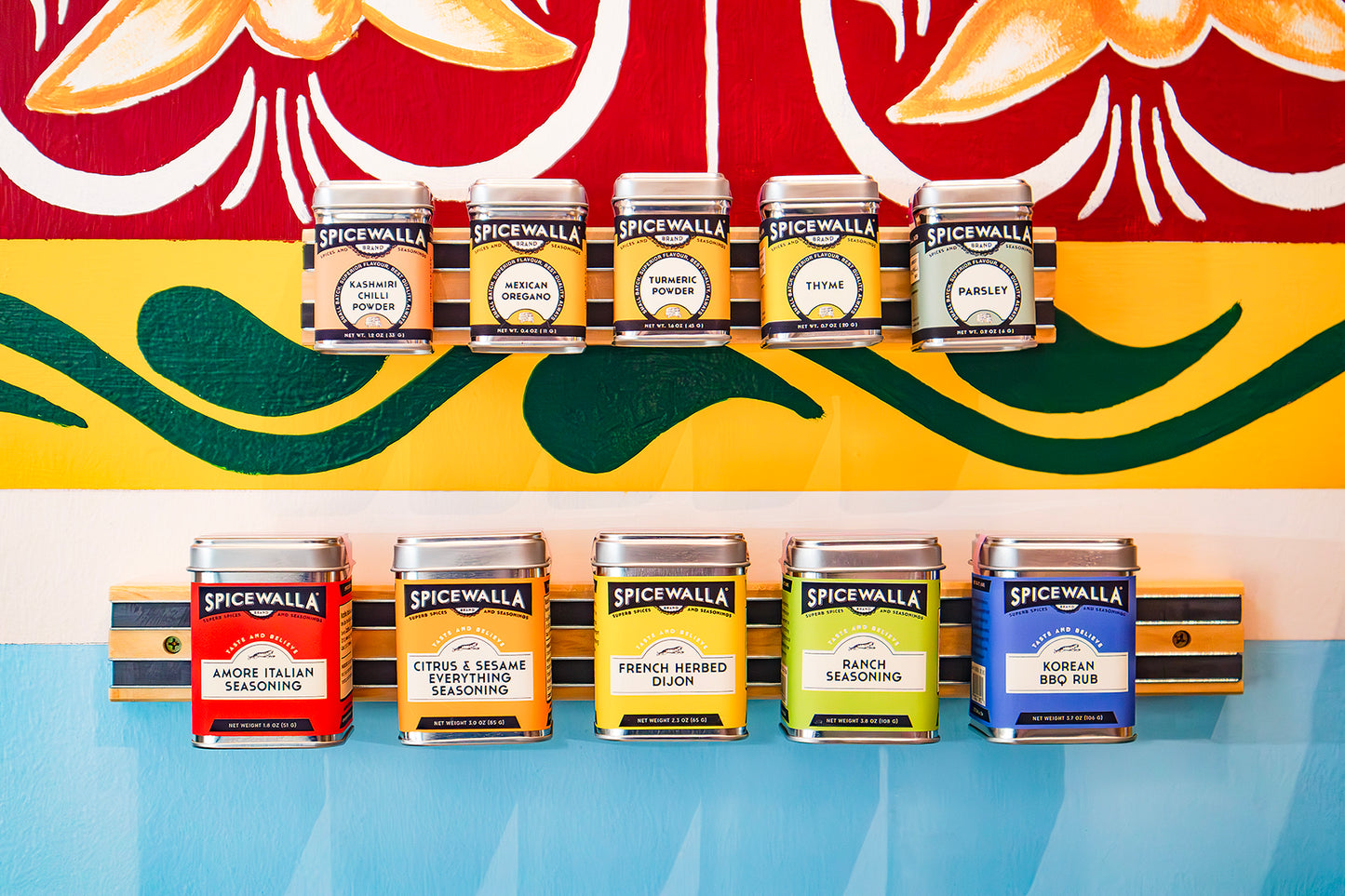 Spicewalla seasoning cans displayed against a colorful abstract background