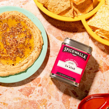 Spicewalla za'atar spice container with hummus and chips on a textured surface