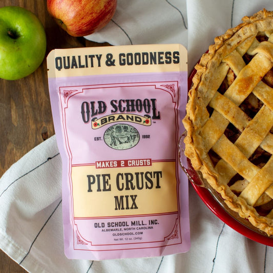 Old School Brand pie crust mix package with a pie and apples on a wooden table.