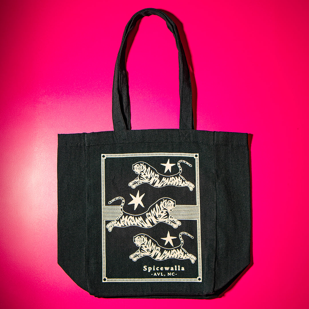 Black tote bag with white tiger design on a pink background