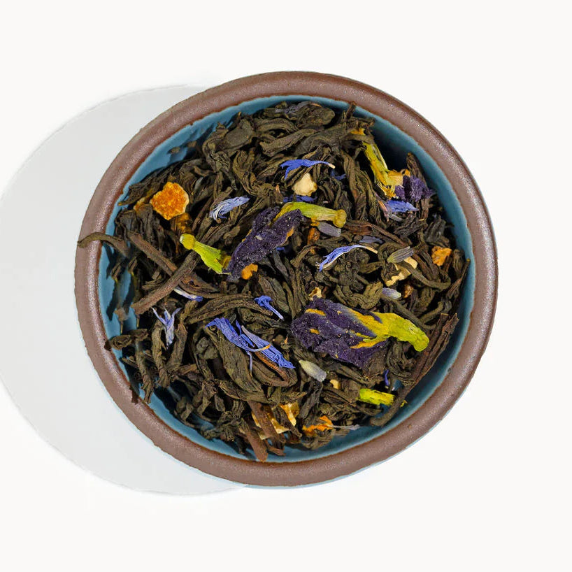 Tea leaves with visible colors in a ceramic bowl on a white background