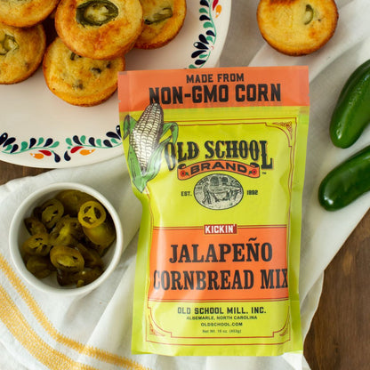 Old School Brand jalapeño cornbread mix package with cornbread muffins and jalapeños on a wooden surface.