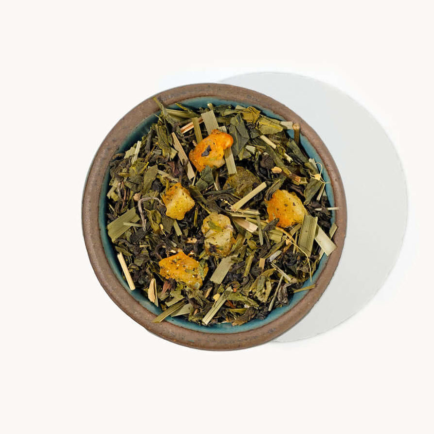 Tea leaves with orange flowers in a wooden bowl on a white background